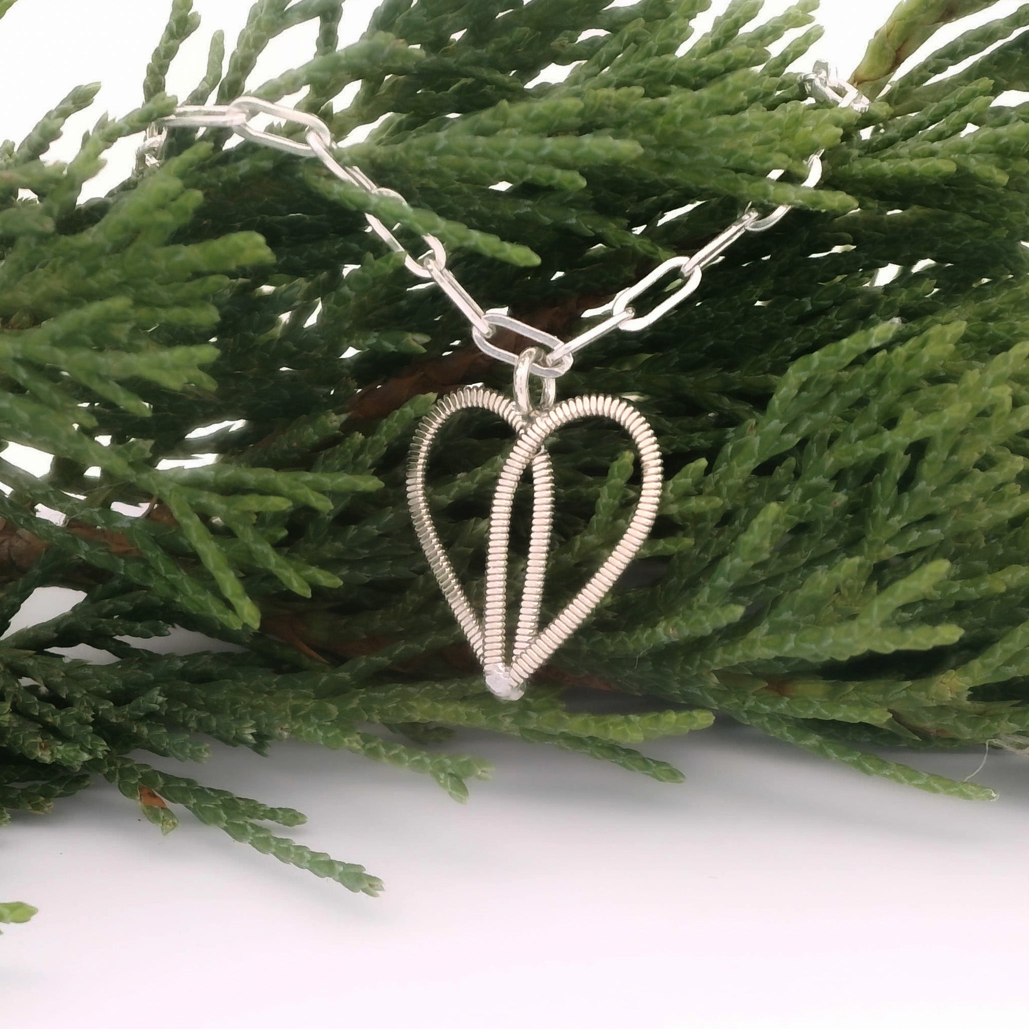 Silver paperclip chain bracelet with guitar string heart on pine branch