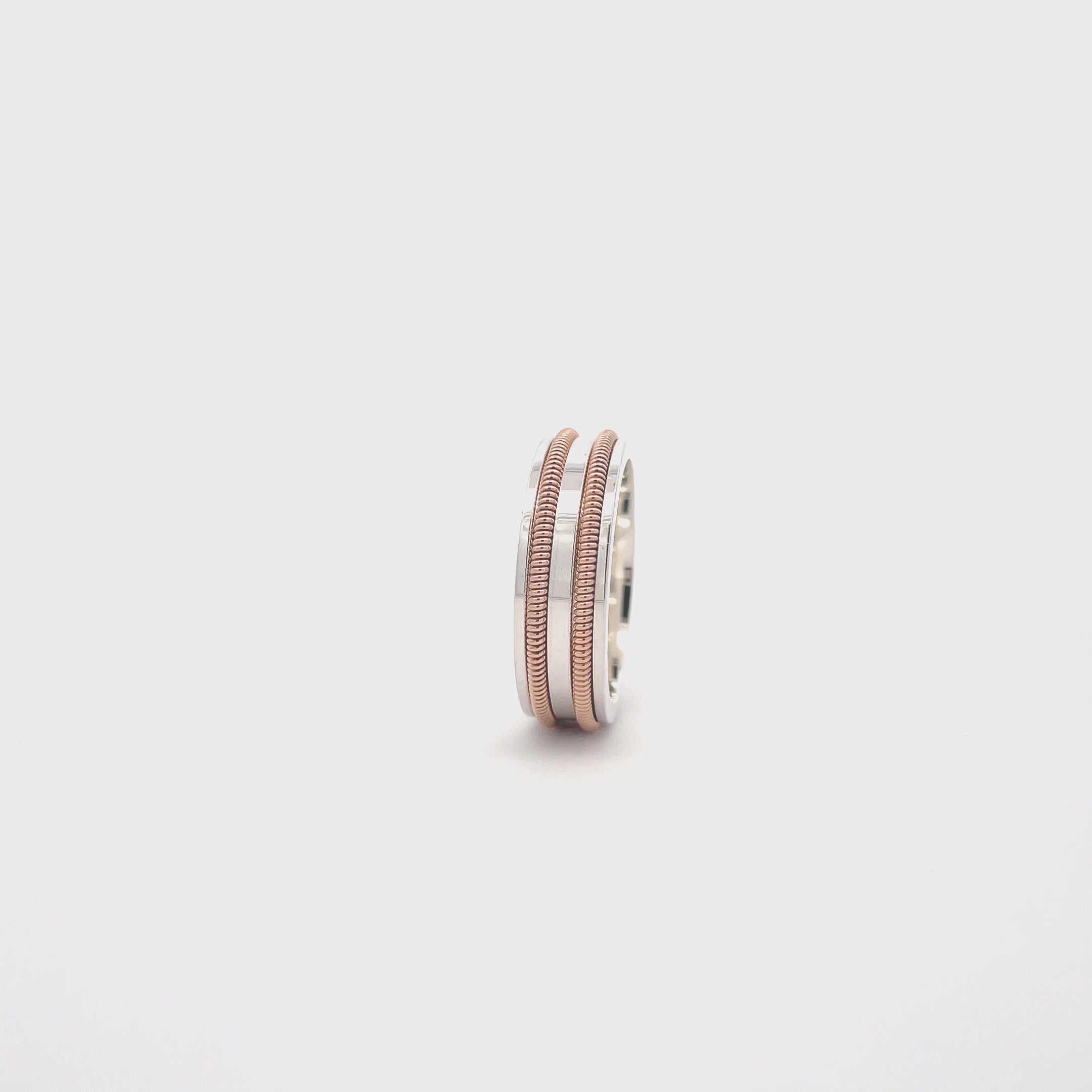 silver ring with embedded guitar string rotating on a white surface