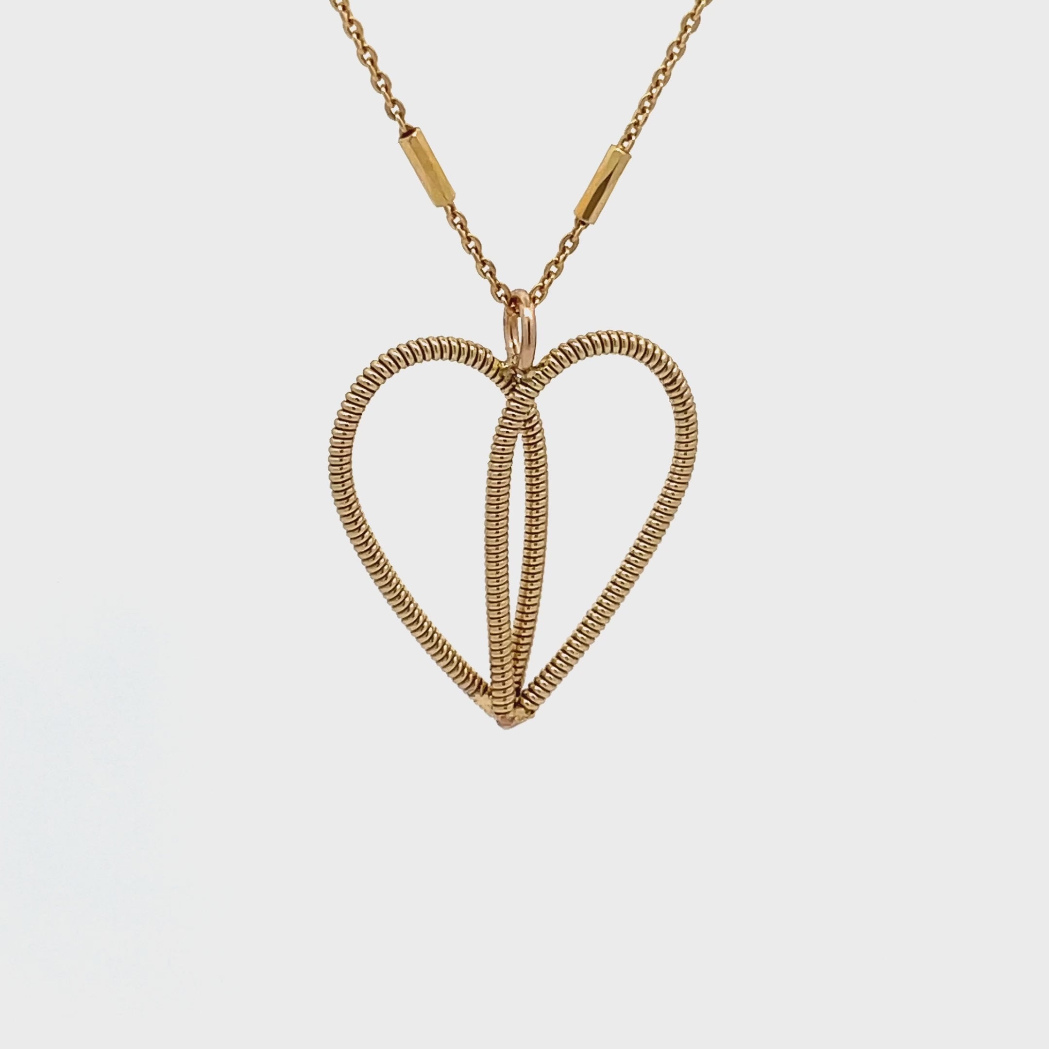 Gold guitar string heart necklace rotating on a white background and turning into a white gold guitar string heart necklace