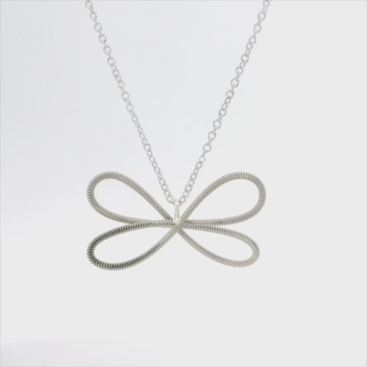 Electric guitar string dragonfly necklace on a white background