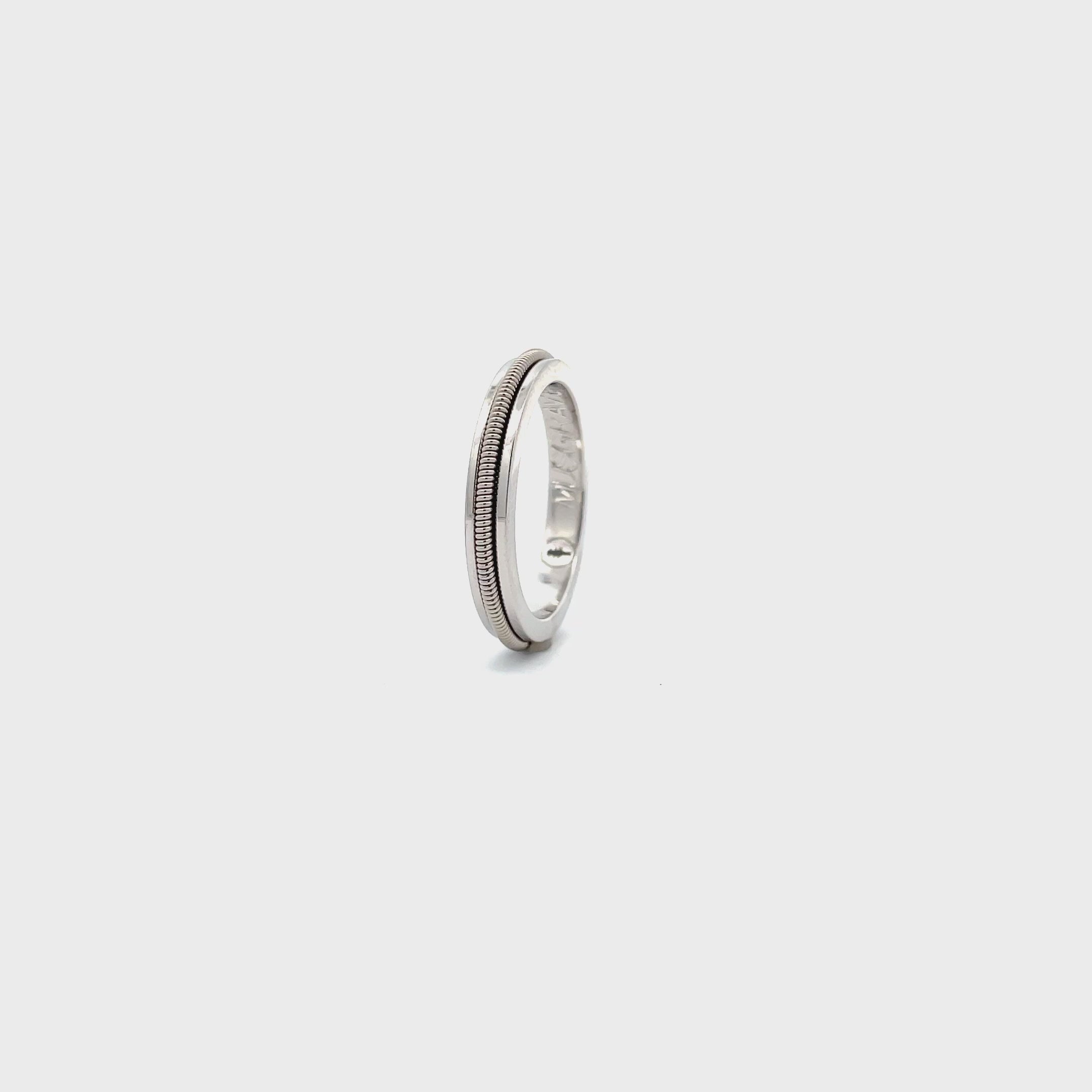 silver ring with embedded electric guitar string rotating on a white surface