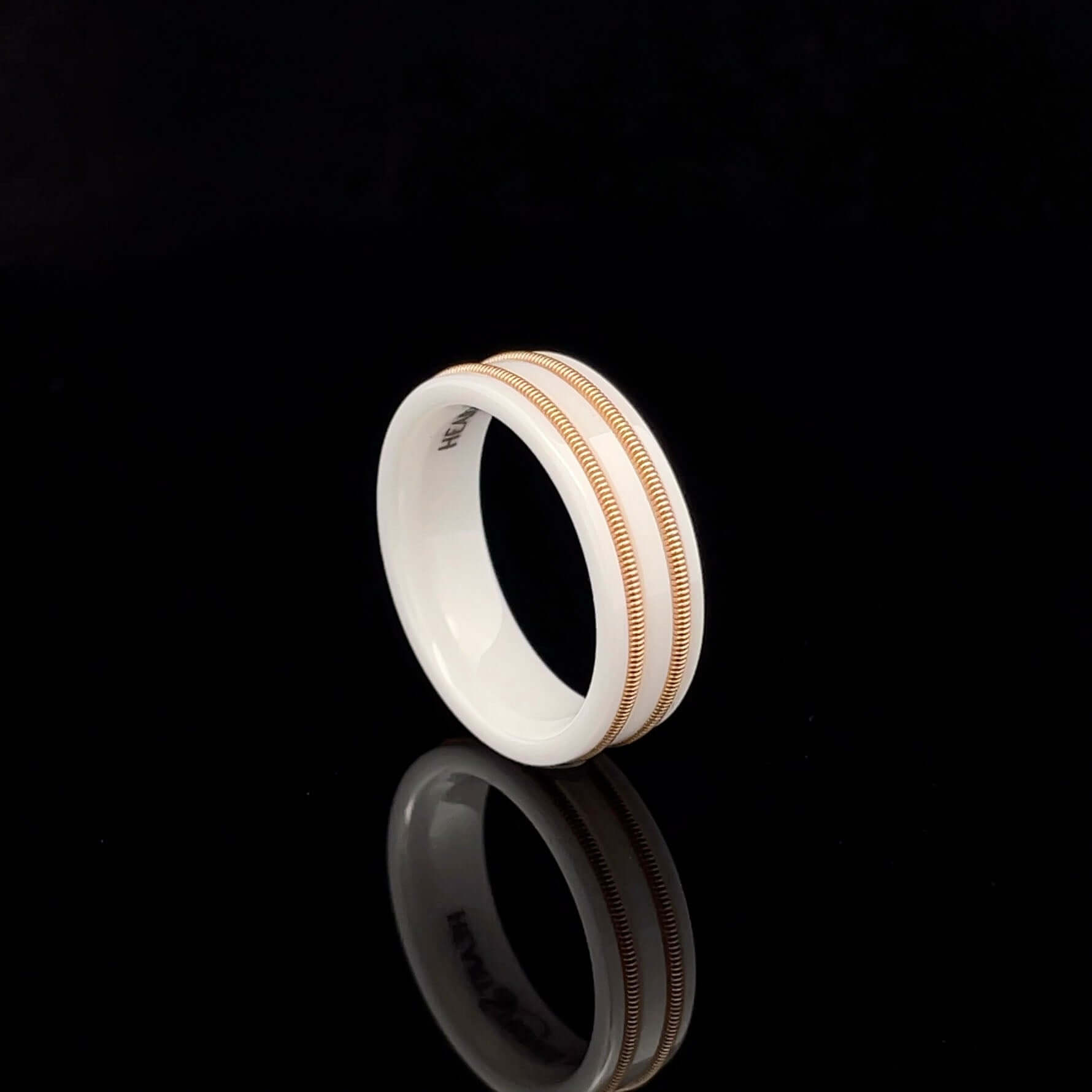 White luminous ring with embedded bronze guitar string on a black background.