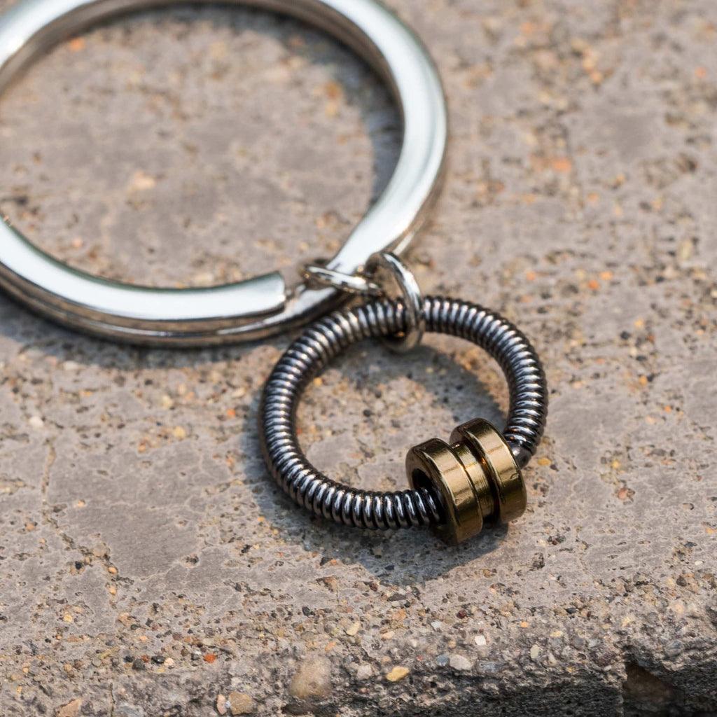 bass guitar string keychains in gold laying on cement