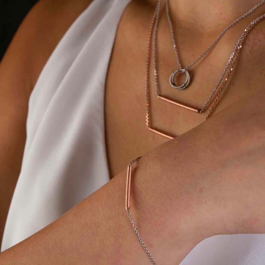Piano string and white gold bracelet and piano string necklaces on model in white top