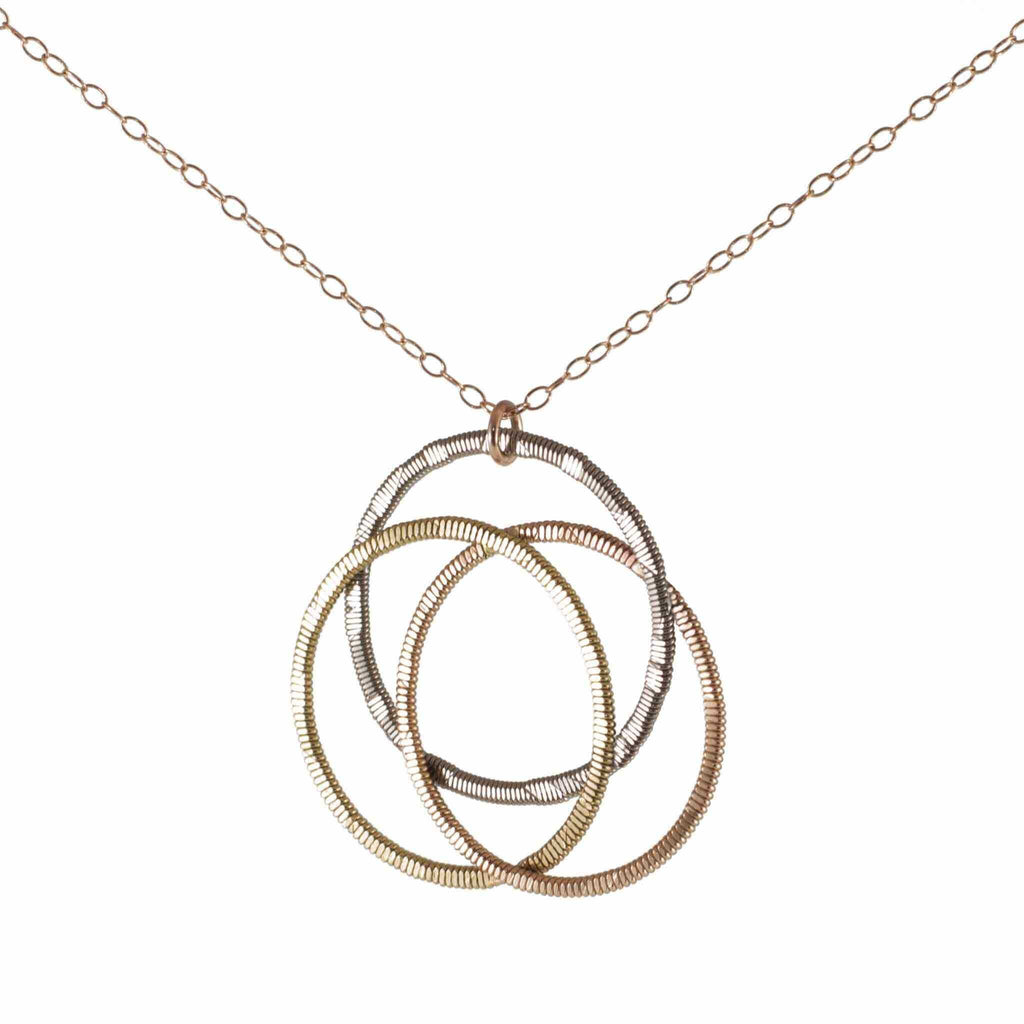 Celtic knot made from acoustic and electric guitar string on a rose gold chain with white background