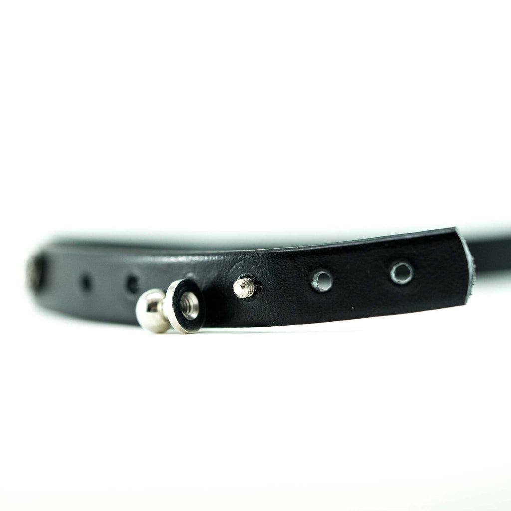woven electric guitar string and black leather bracelet with ball clasp on a white background