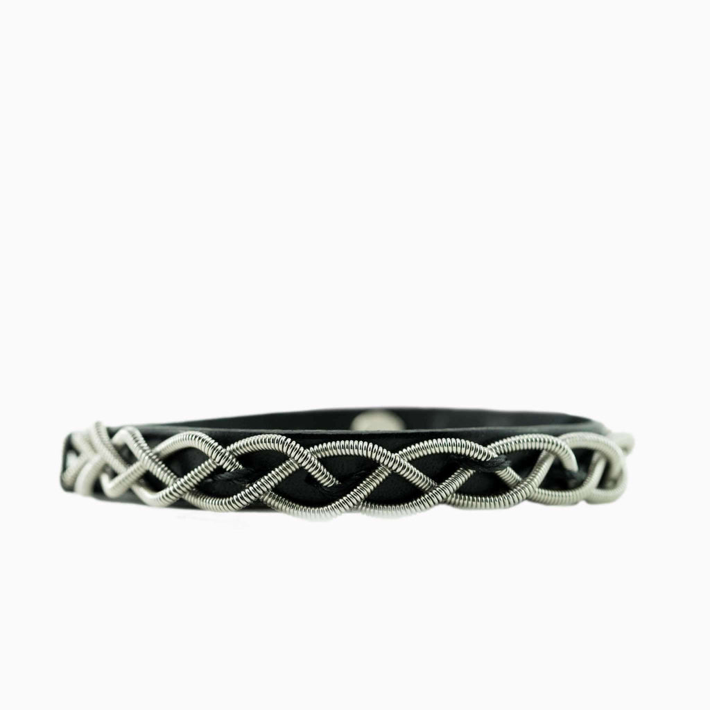 electric base guitar string and black leather bracelet laying on white background
