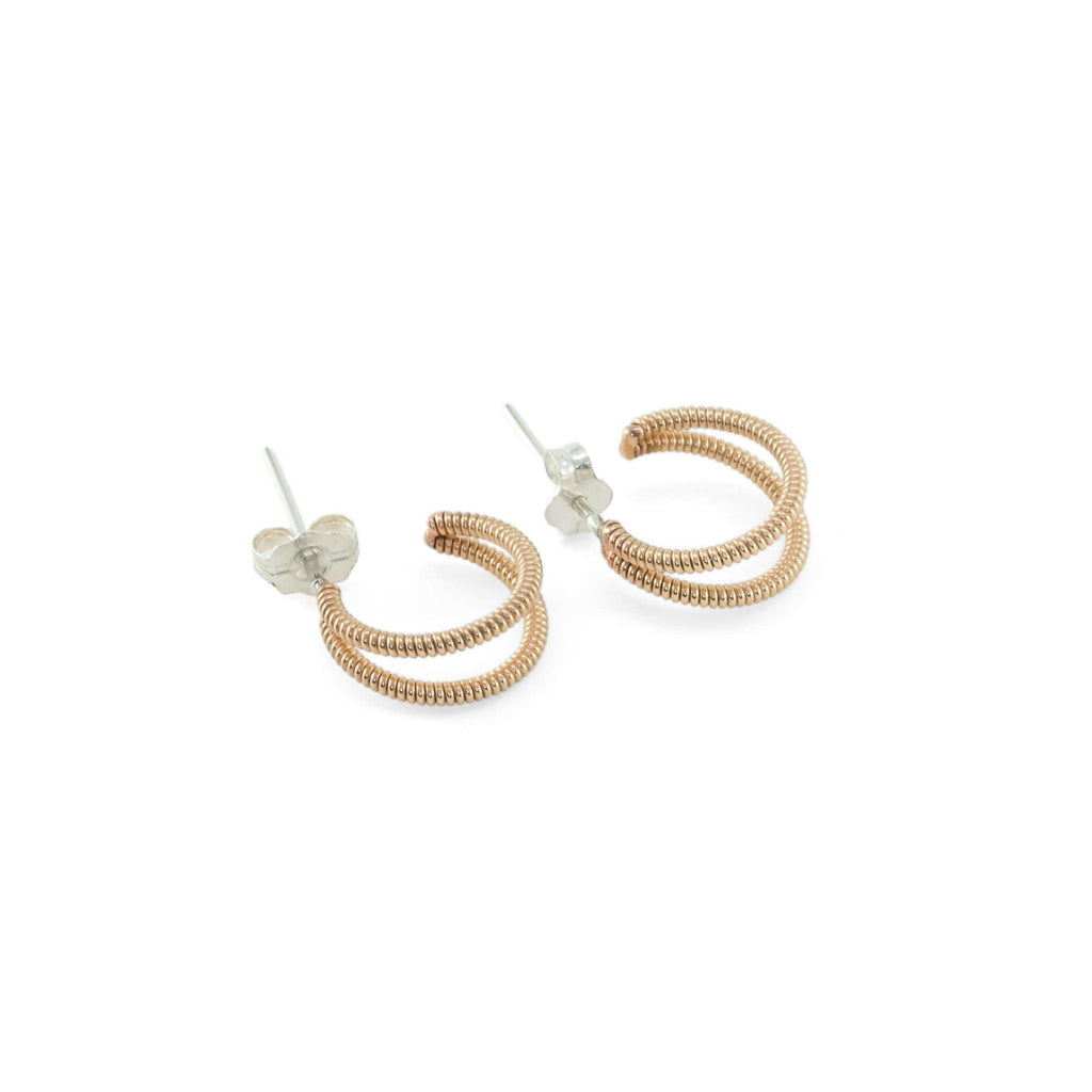 crescent shaped huggie guitar string earrings on a white background