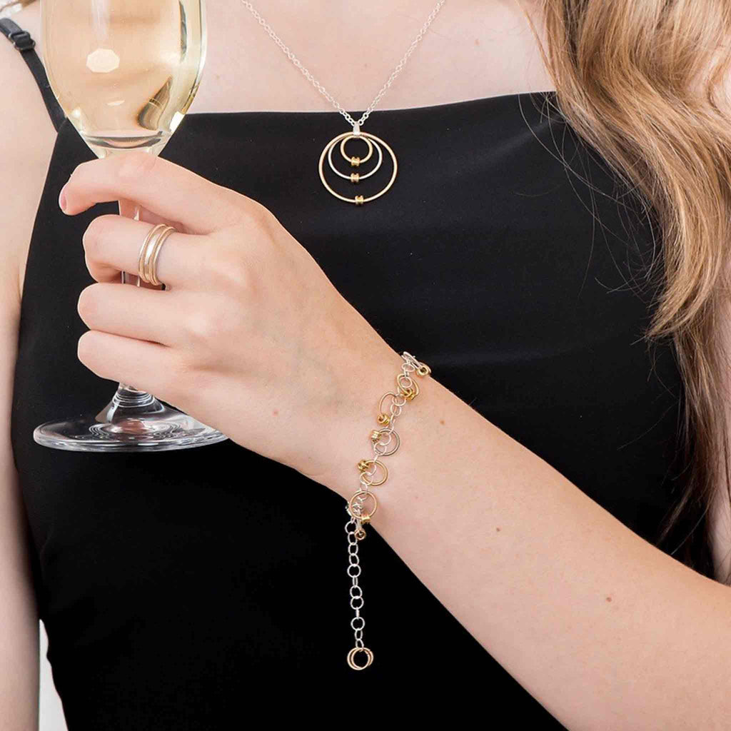 girl in a black dress holding a glass of champagne and wearing a guitar string necklace and bracelet