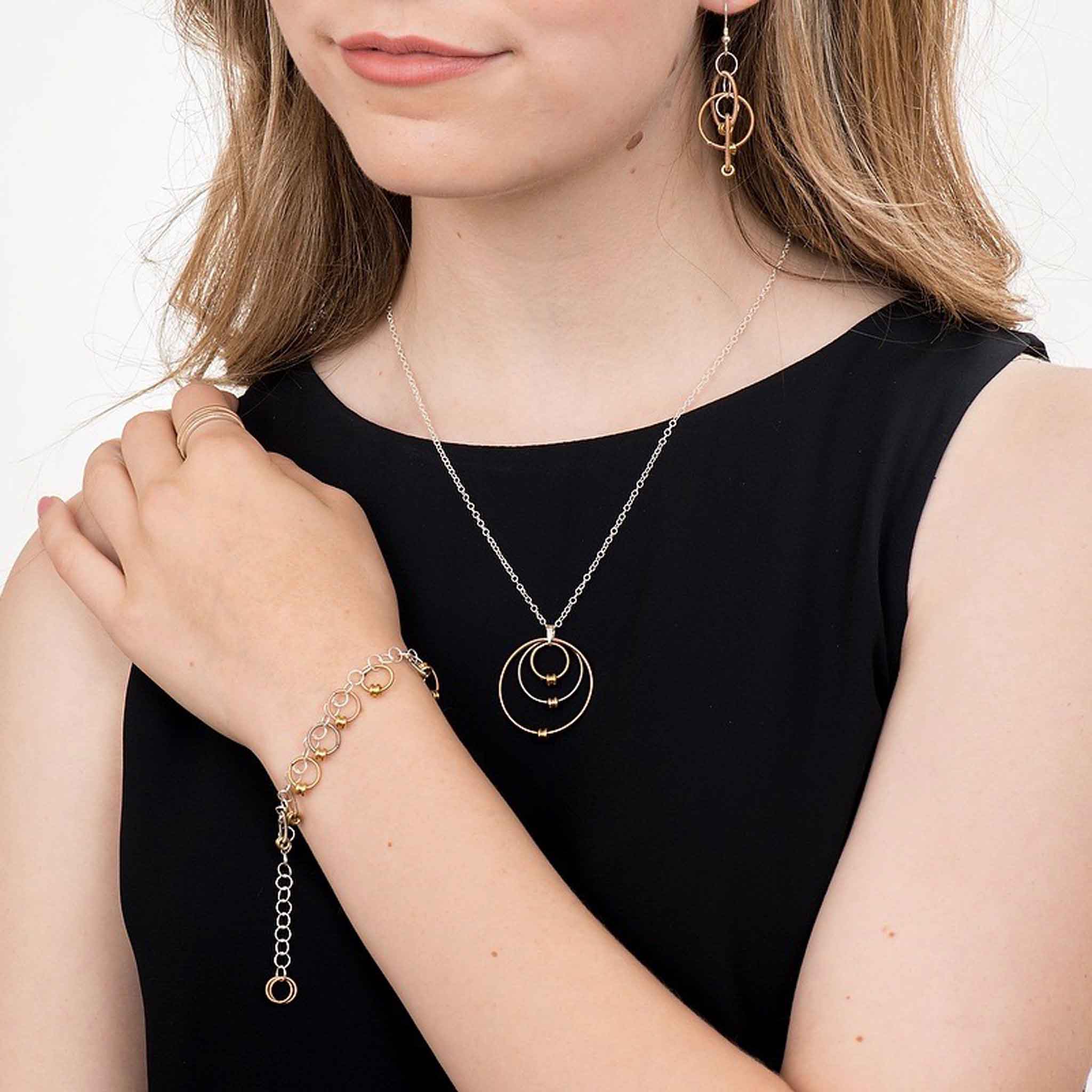 girl in a black dress holding a glass of champagne and wearing a guitar string necklace, earrings,  and bracelet