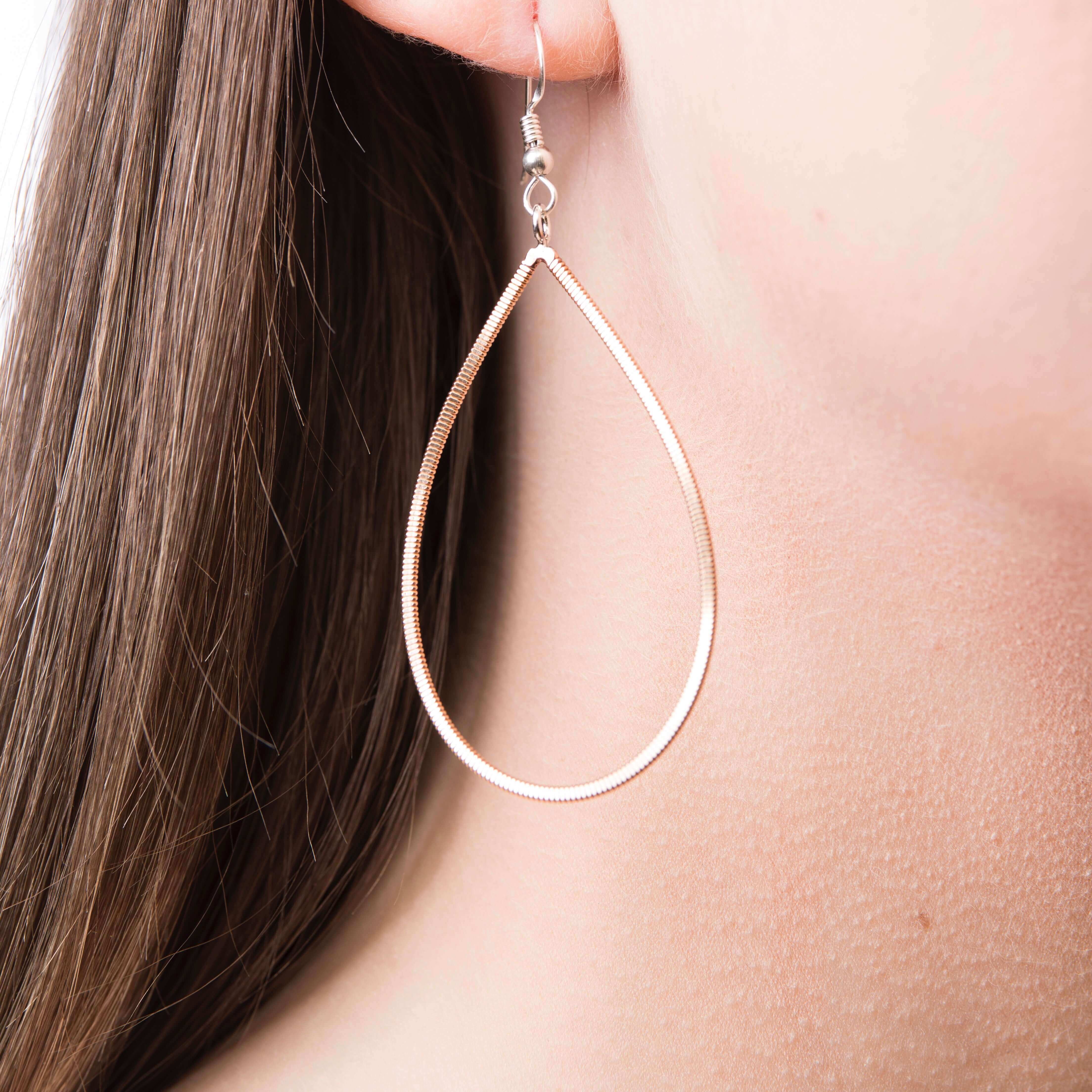 Close up of model wearing guitar string drop earring 