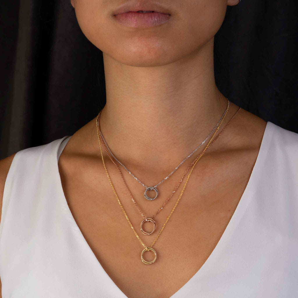 Layered gold, rose gold, and white gold guitar string necklaces on model