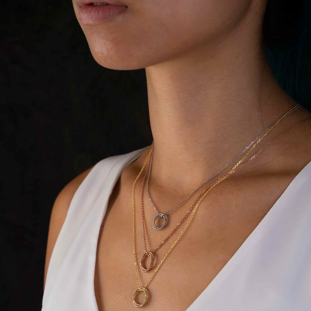Layered gold, rose gold, and white gold guitar string necklaces on model, side view