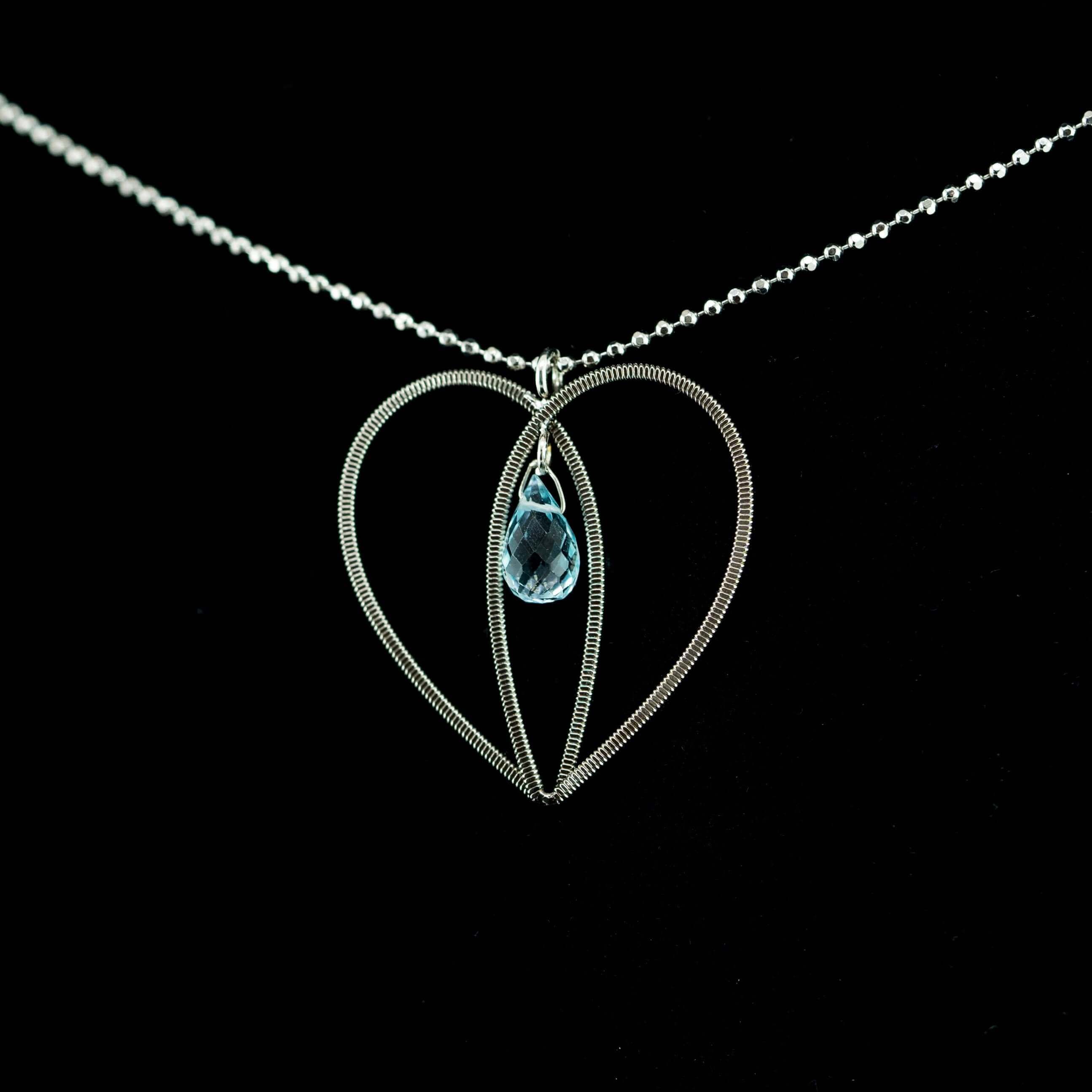 Electric guitar sting heart with aquamarine gemstone hanging on black background