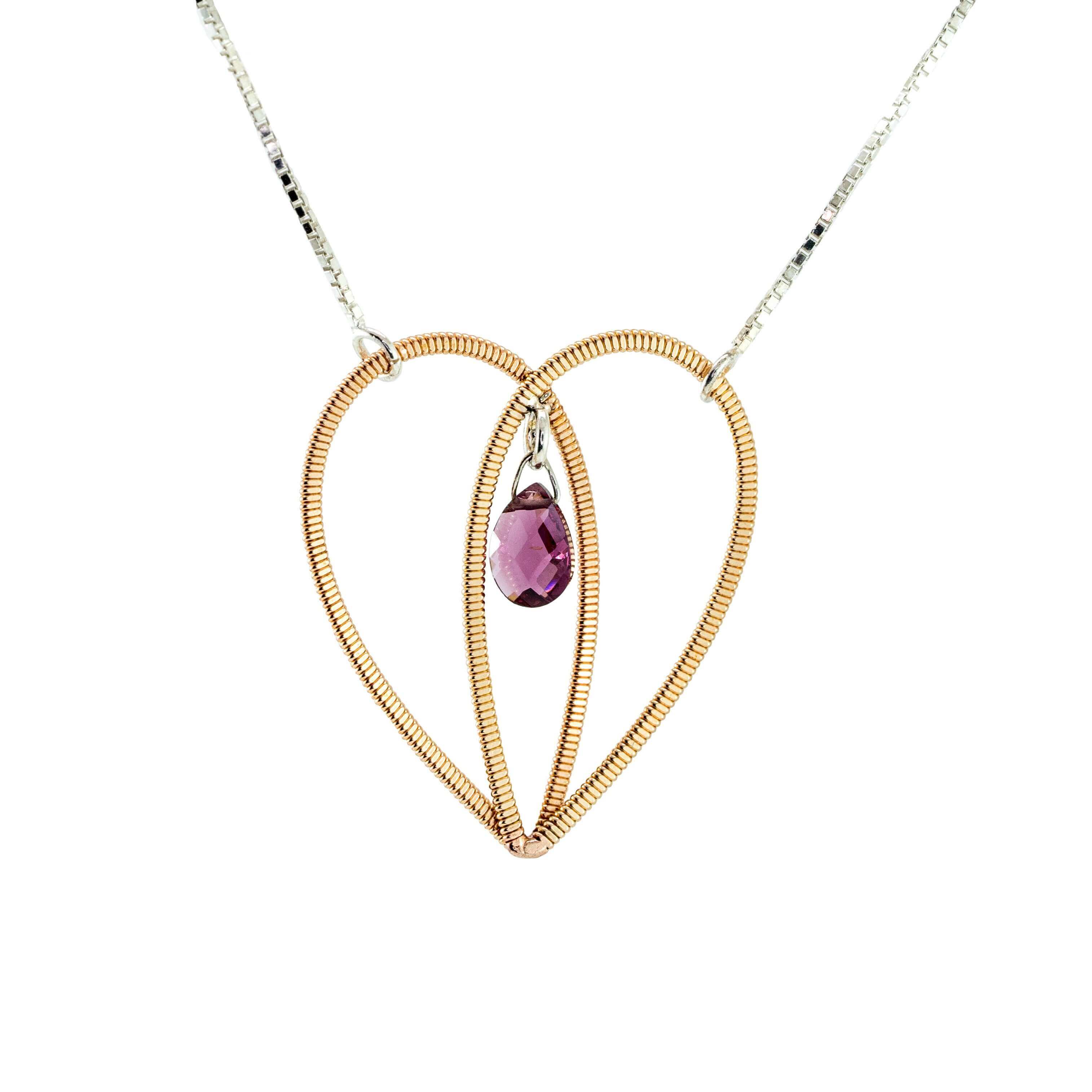 Acoustic guitar string heart pendant with a garnet gemstone suspended in the centre on a silver box chain on a white background