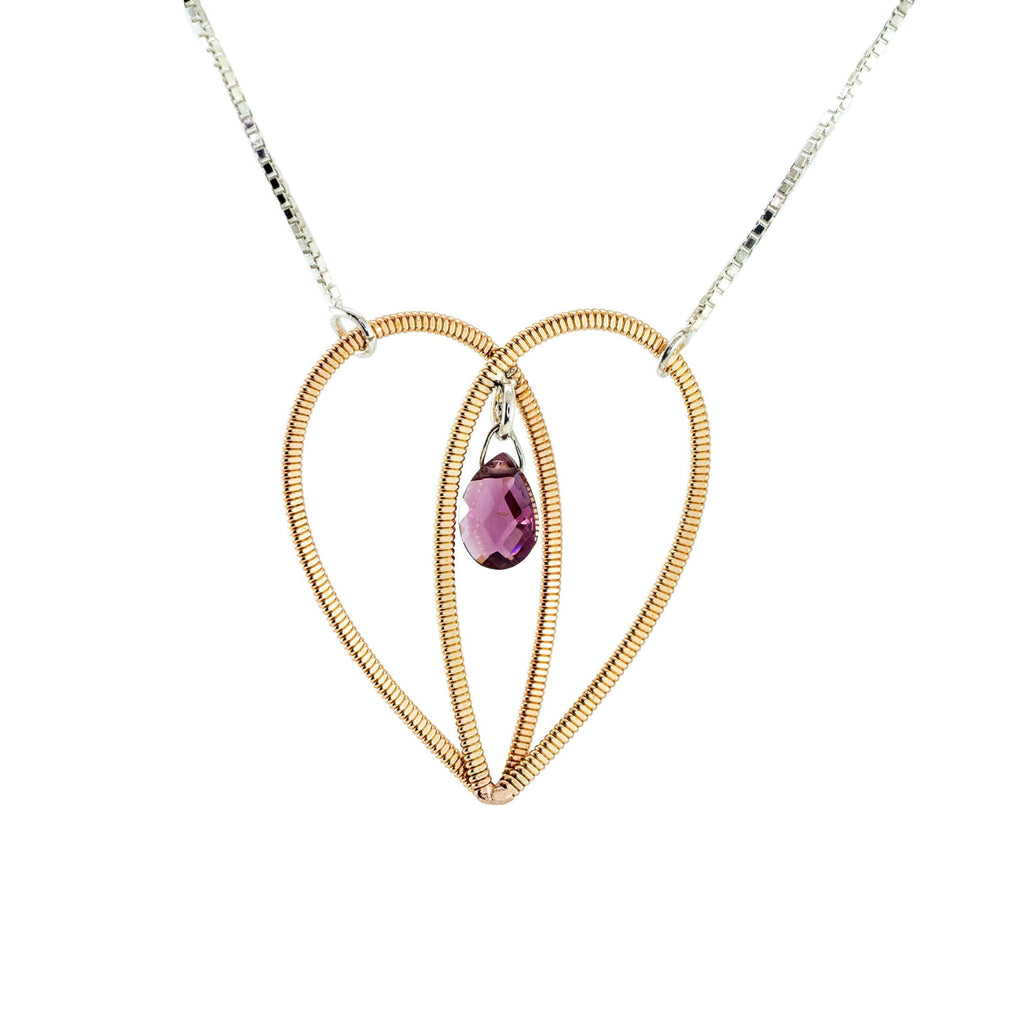Acoustic guitar string heart pendant with a garnet gemstone suspended in the centre on a silver box chain on a white background