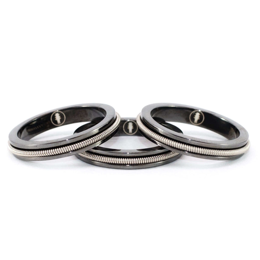 3 black rings with embedded electric guitar string