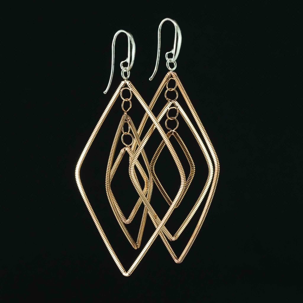 floating diamond-shaped dangling guitar string earrings with silver ear hooks on a black background