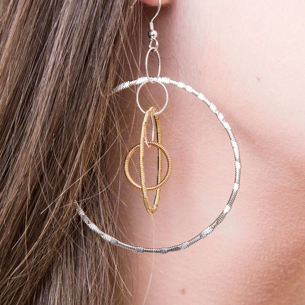Reclaimed guitar string dangle earrings with inter-set hoops, close-up on model.