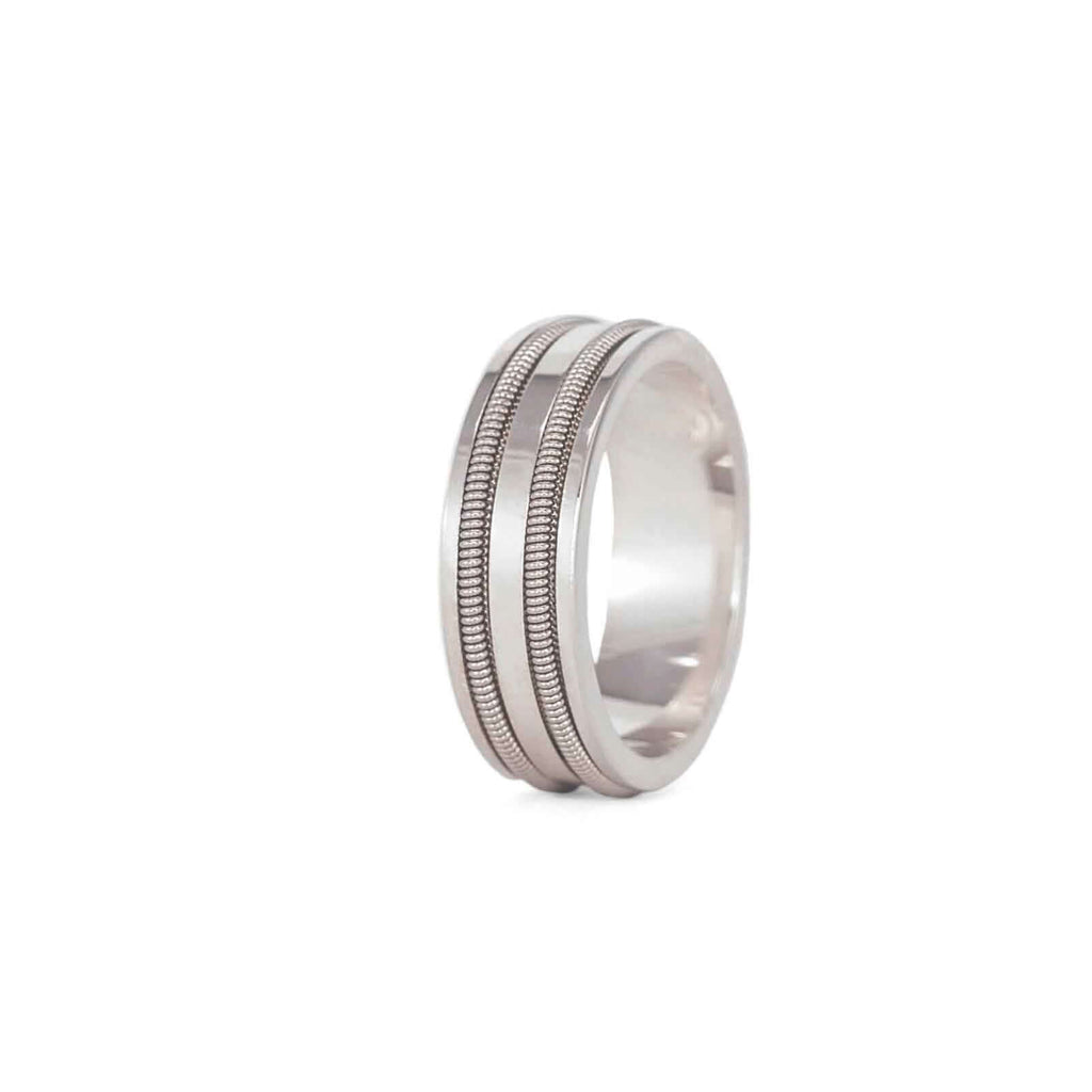 Silver ring with two rows of embedded electric guitar string on a white background