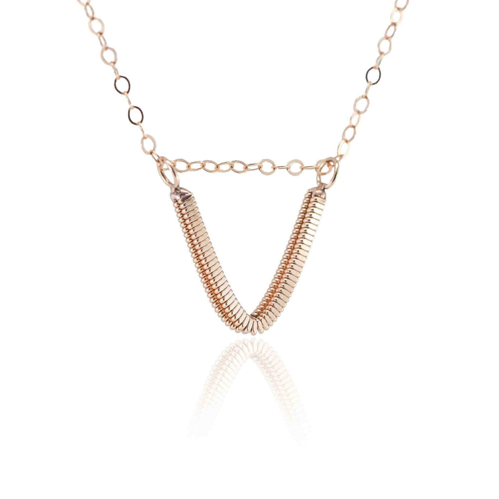 Rose gold guitar string v-necklace hanging with white background and reflection