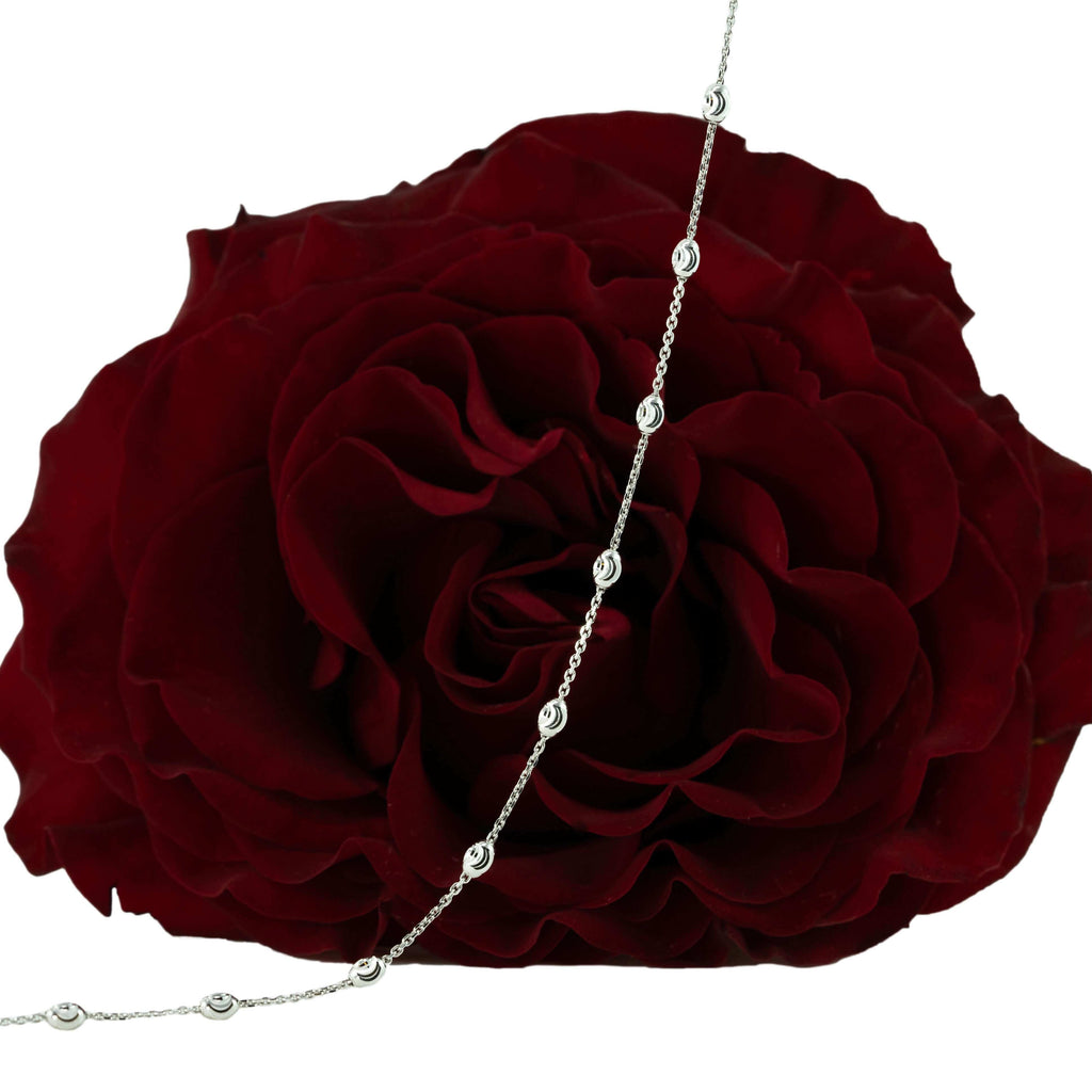 18K white gold chain with moon-cut with gold beads hanging on in front of a red rose
