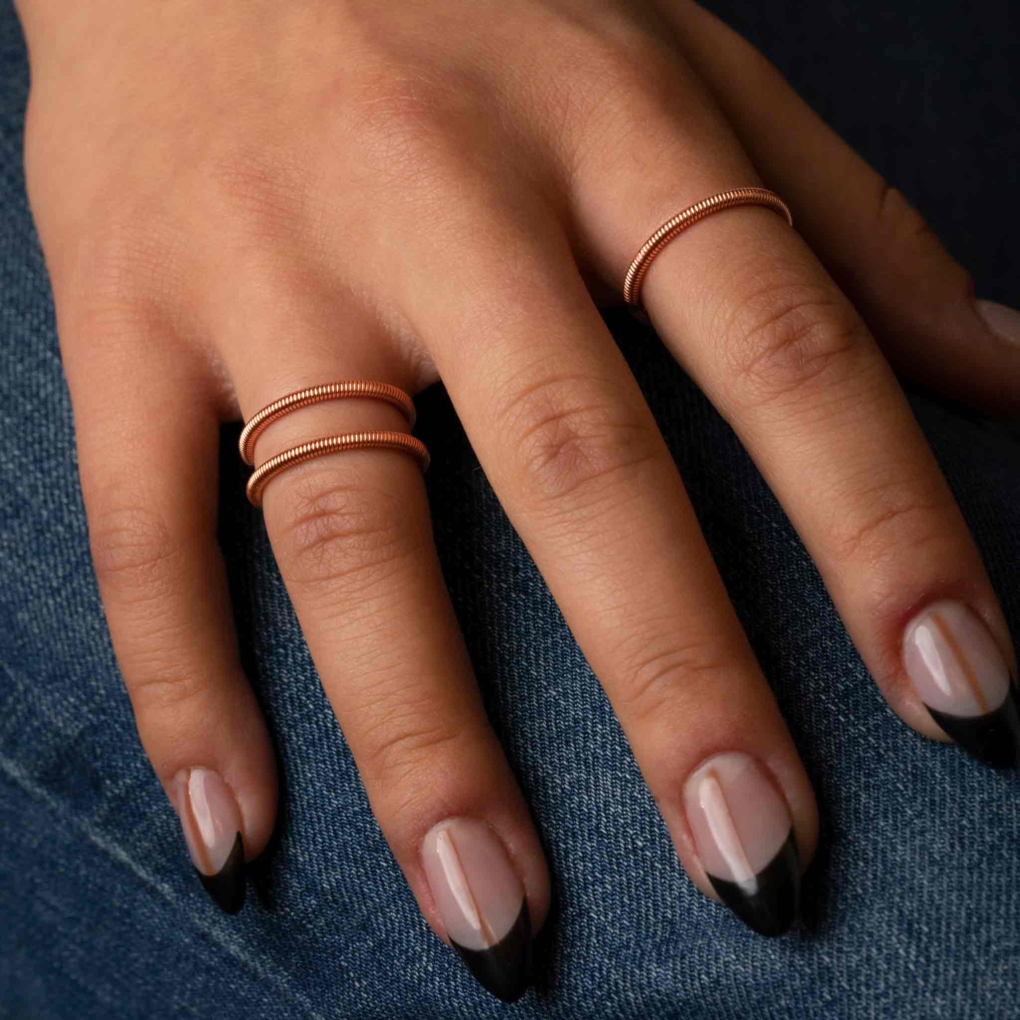 Piano and guitar string rings on model wearing jeans