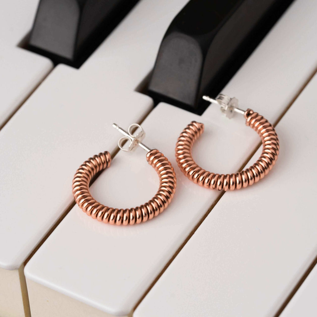 Piano string hoop earrings laying on the piano keys of a piano