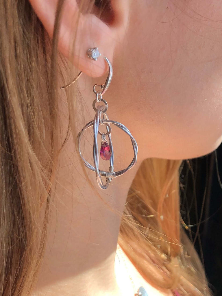 Violin string double hoop earrings with garnet gemstones on a model